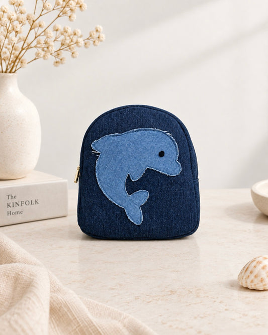 A small dark blue upcycled denim mini backpack with an applique dolphin design